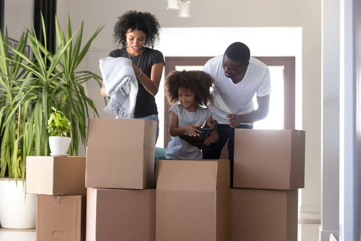 Black parents and child daughter unpacking boxes in new home (R) (S)