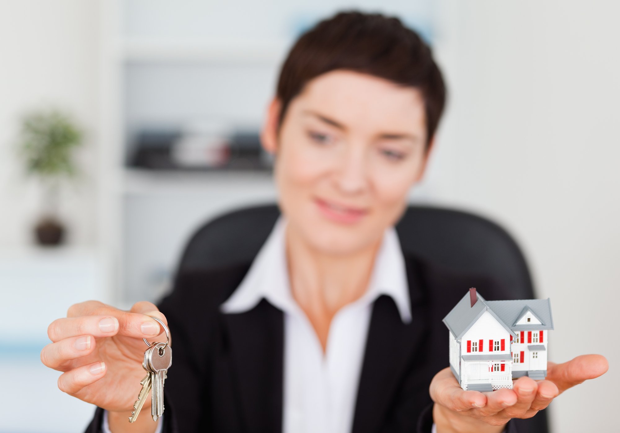 Businesswoman showing a miniature house and a key