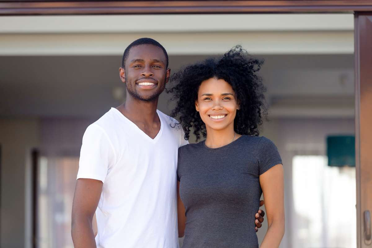 Portrait of happy black couple posing outside own home (R) (S)